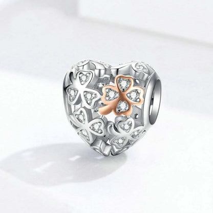 Heart-shaped sterling silver charm bead with clover motif and rose gold center detailing.