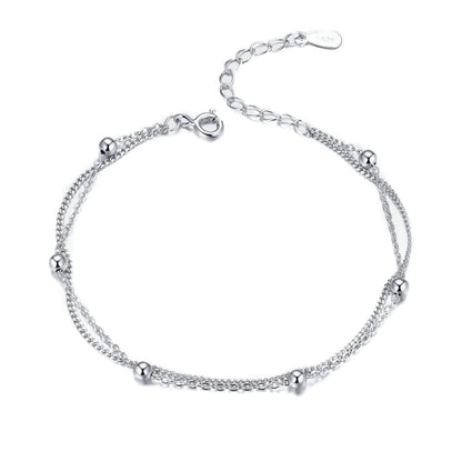 Silver bracelet with delicate chain links and small round charm details, lobster clasp.