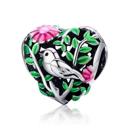 Heart-shaped silver charm bead with bird, green leaves, and pink flower enamel details