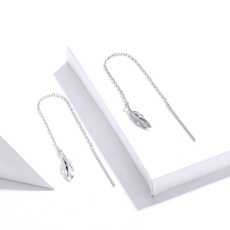 Pair of long silver-tone feather drop earrings on display stand