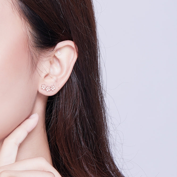 Rose gold flower CZ stud earrings on model, close-up ear view