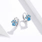 Blue-stone cat paw hoop earrings in sterling silver, angled view on ear