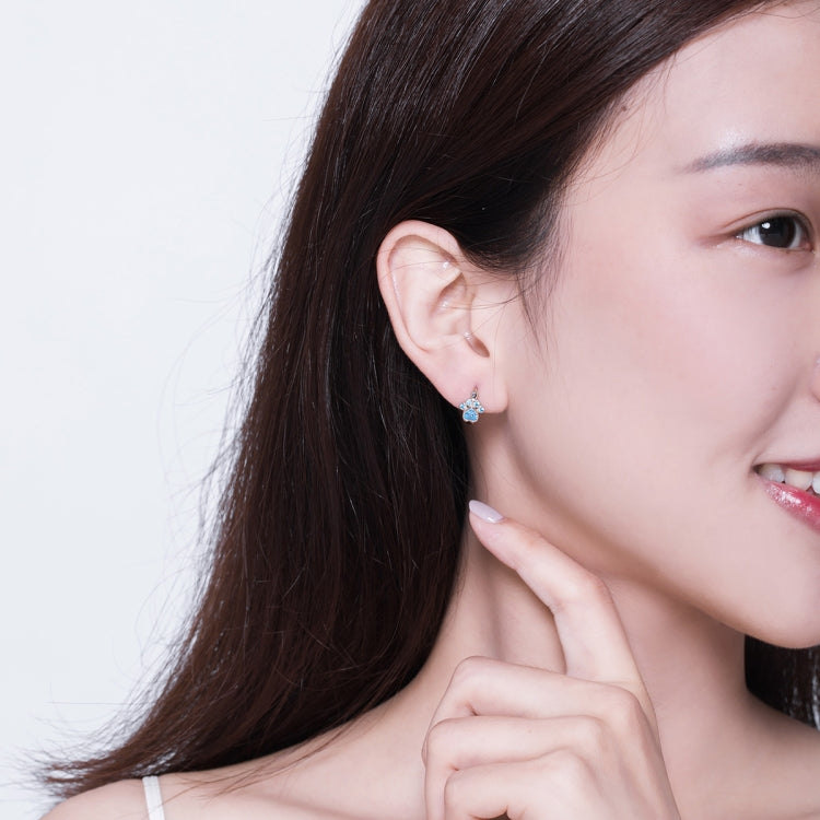 Woman wearing small sterling silver cat paw hoop earrings with blue stones