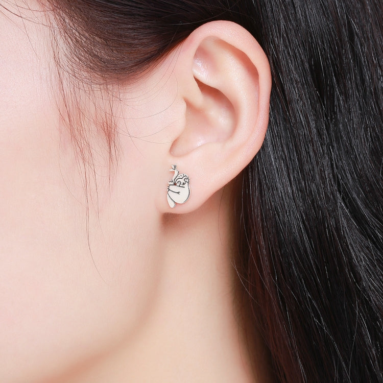Silver sloth stud earrings on ear, leaf-topped oval face design