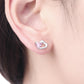 Heart stud earrings with pink gemstone on a wearer's ear, sterling silver finish