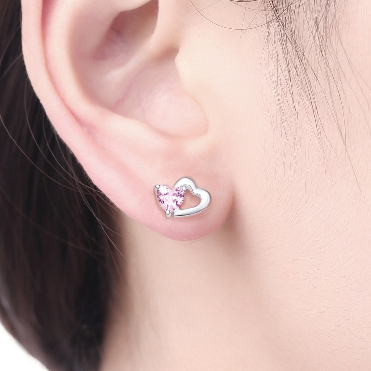 Heart stud earrings with pink gemstone on a wearer's ear, sterling silver finish