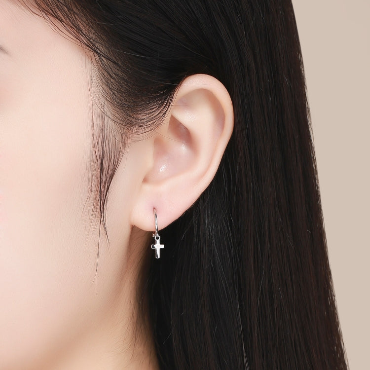 Cross hoop earrings worn on ear with dangling cross charm