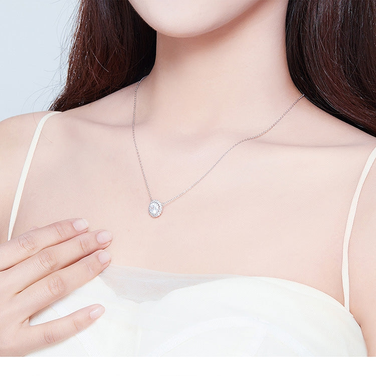 Silver zircon pendant necklace worn on neckline with round halo center stone