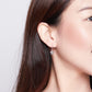 Sterling silver heart earrings with a dangling open heart on a model