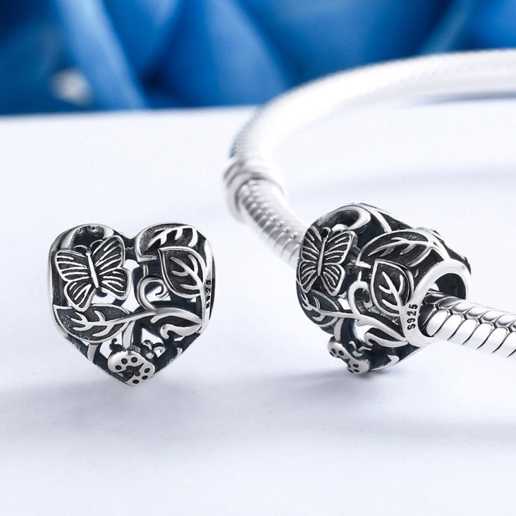 Sterling silver heart charm bead with butterfly and garden motifs on a bracelet