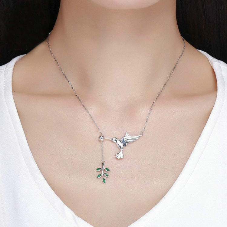 Sterling silver hummingbird necklace worn with green enamel flower charm