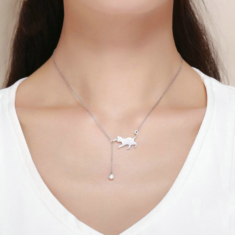 Silver cat charm necklace worn on neckline with small teardrop CZ pendant