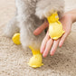 Yellow silicone pet rain boots set with cartoon paw bottoms; hand fitting boot on dog