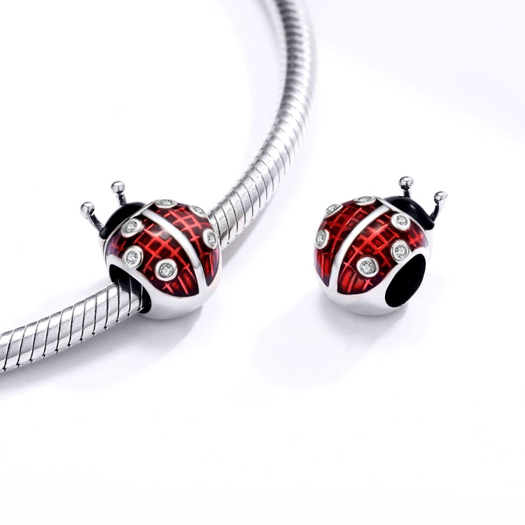 Ladybug charm bead with red enamel on a silver snake bracelet strand