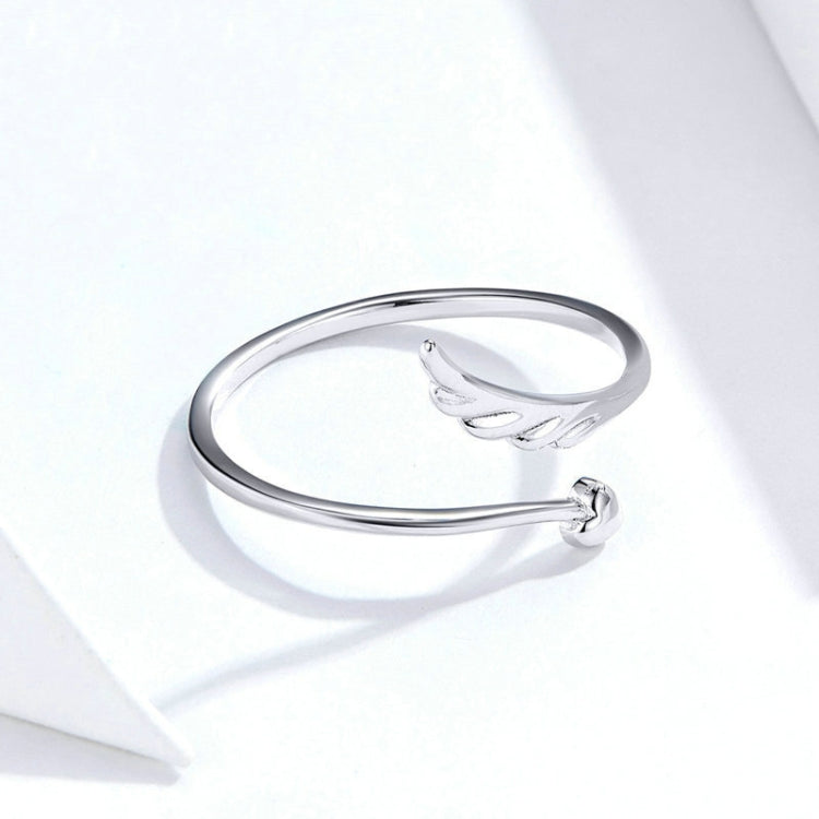 Silver open angel wing ring with slender band, angled close-up