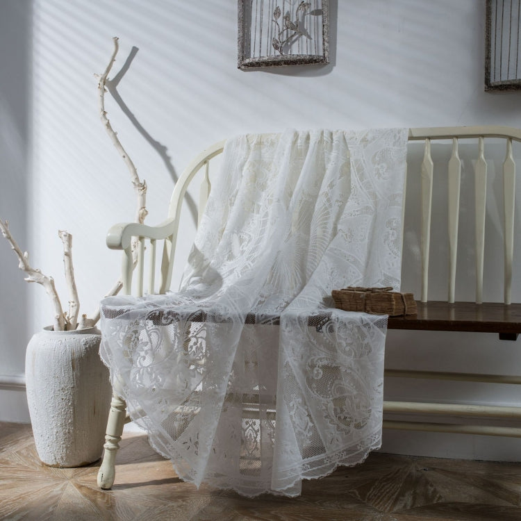 White lace tablecloth with scalloped hem and floral lace overlay on table