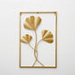 Gold metal leaf wall hanging in a square frame with three ginkgo-style leaves