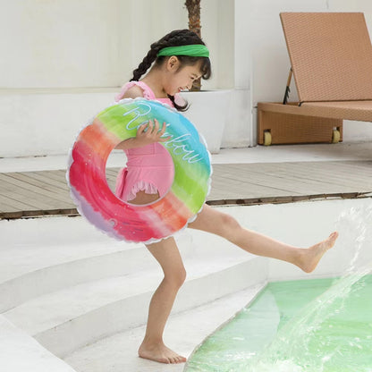 Kids rainbow gradient PVC swimming ring with “Rainbow” script, held by child in pool