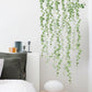 Green leaf dangling wall stickers arranged in layered draping vines on a white wall