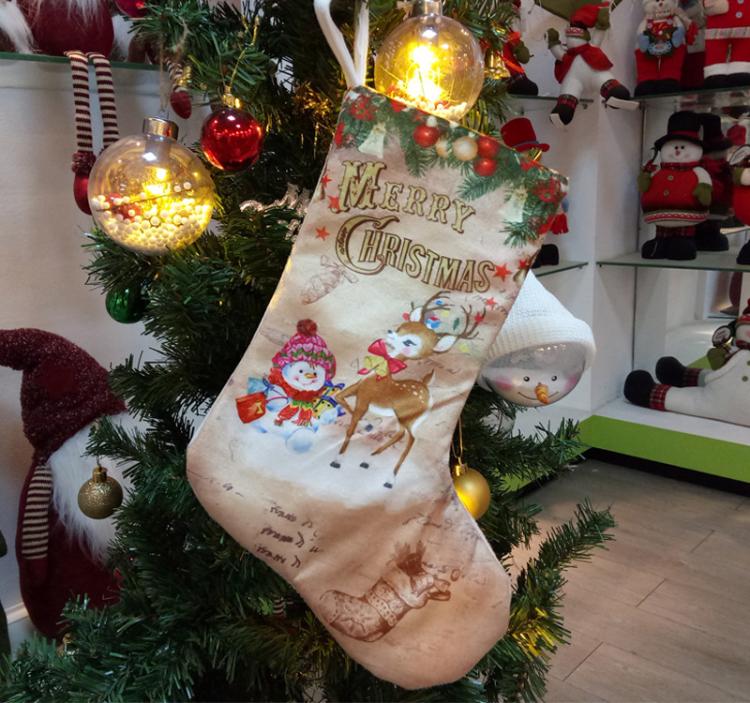 Beige Christmas stocking with 'Merry Christmas' and winter character print, hanging.
