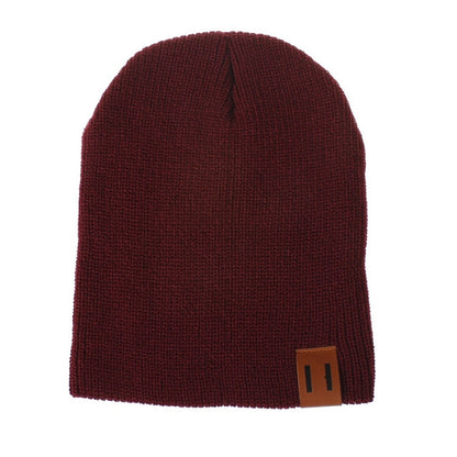 Dark red knit baby beanie with folded cuff and leather patch label on side