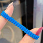 Blue rubber hair band, small loop tie held on a fingertip