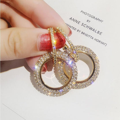 Gold-tone round rhinestone hoop earrings with dangling circle charm, close-up