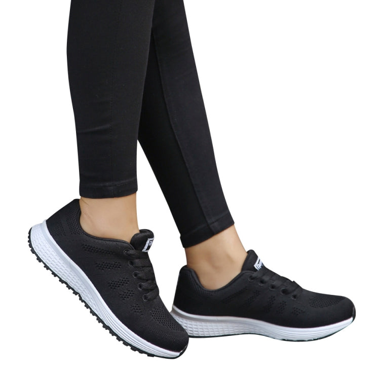 Women's black mesh lace-up sneakers worn with black pants and white midsole