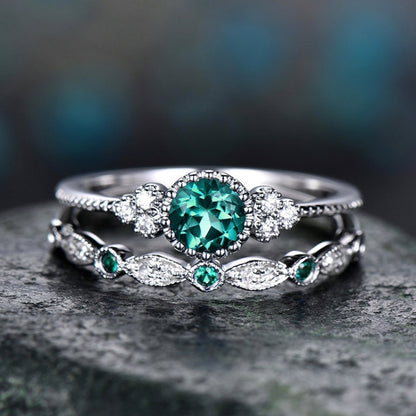 Silver-tone two-ring set with round teal center gemstone and small green accent stones