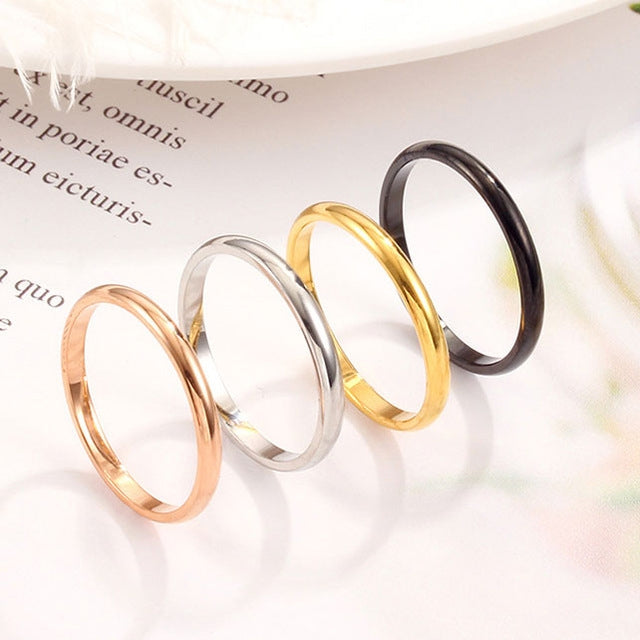 Set of four glossy metal rings: black, gold, rose gold, and silver