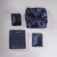 Navy silk-look bedding set pieces laid out: pillowcase squares and sheet fabric