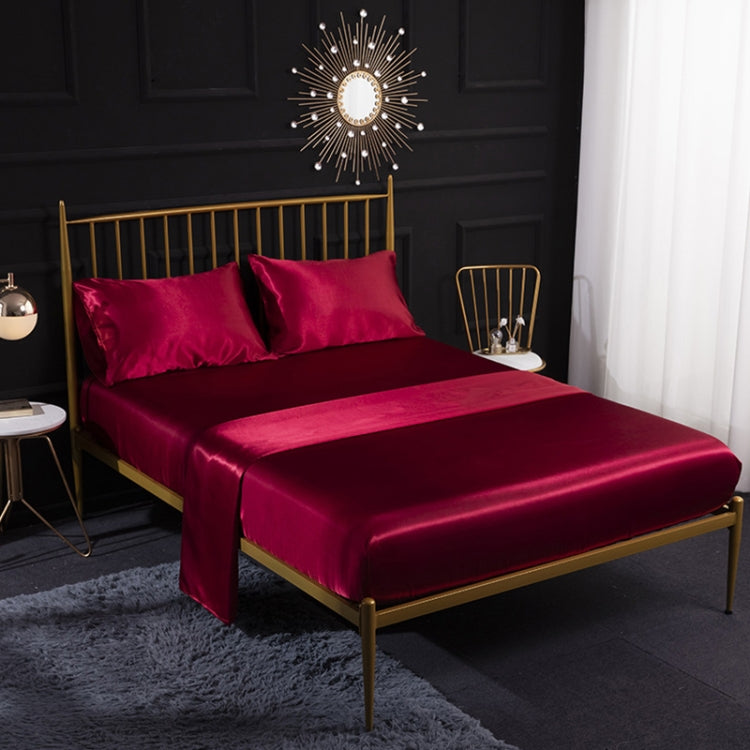 Maroon satin-look four-piece bedding set with pillowcases and fitted sheet on bed