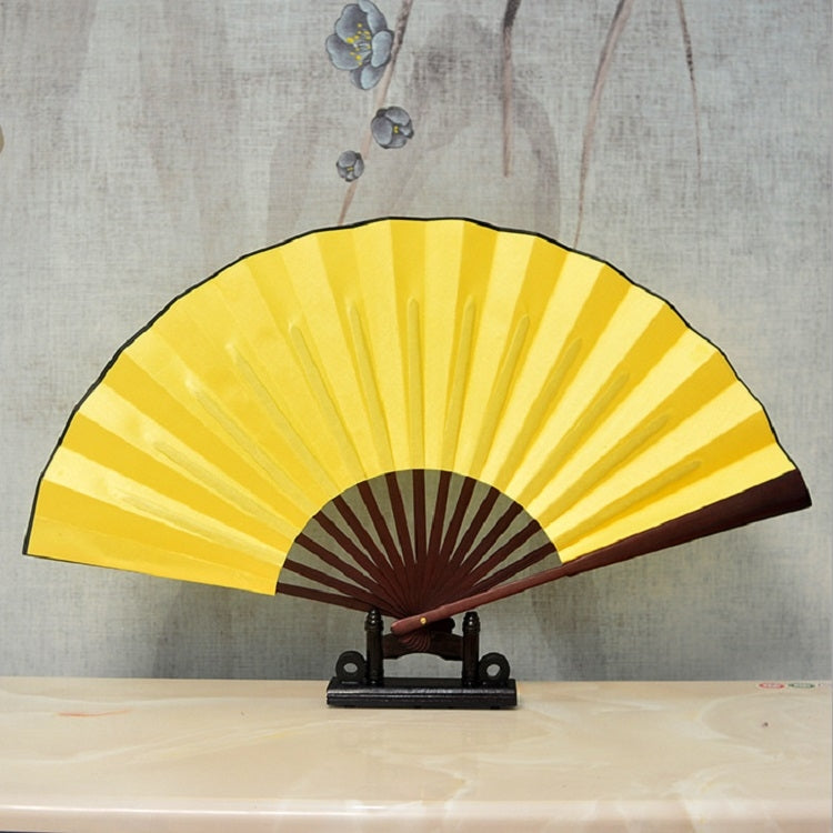 Yellow blank silk folding fan with maroon inner ribs, Chinese-style, on black stand