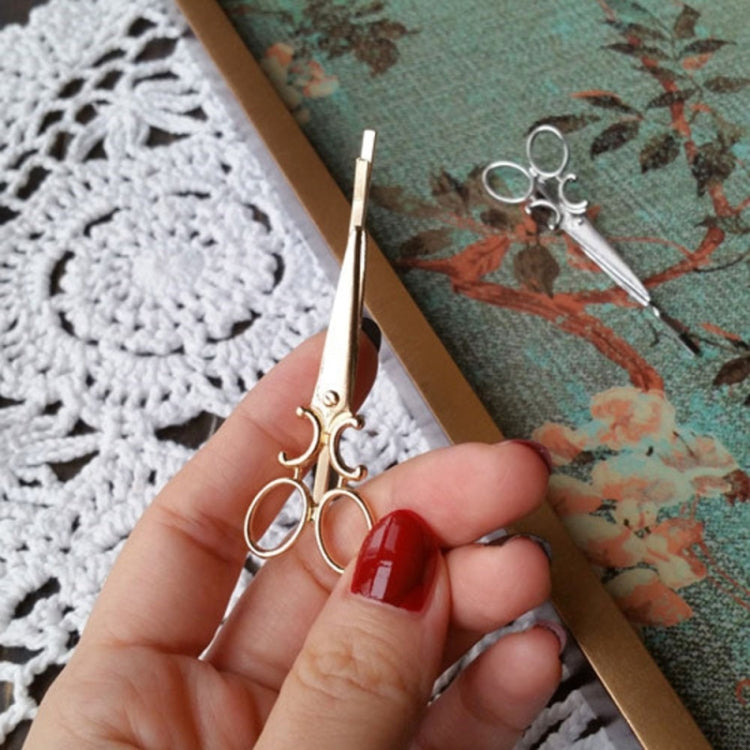Silver ornamental hair clip held in hand, long bar with swirl and ring accents