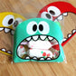 Green monster-mouth cookie gift plastic bag with printed face and visible snacks inside