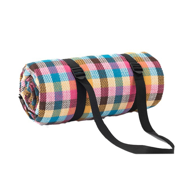 Rolled outdoor camping mat with multicolor check plaid pattern and black securing straps
