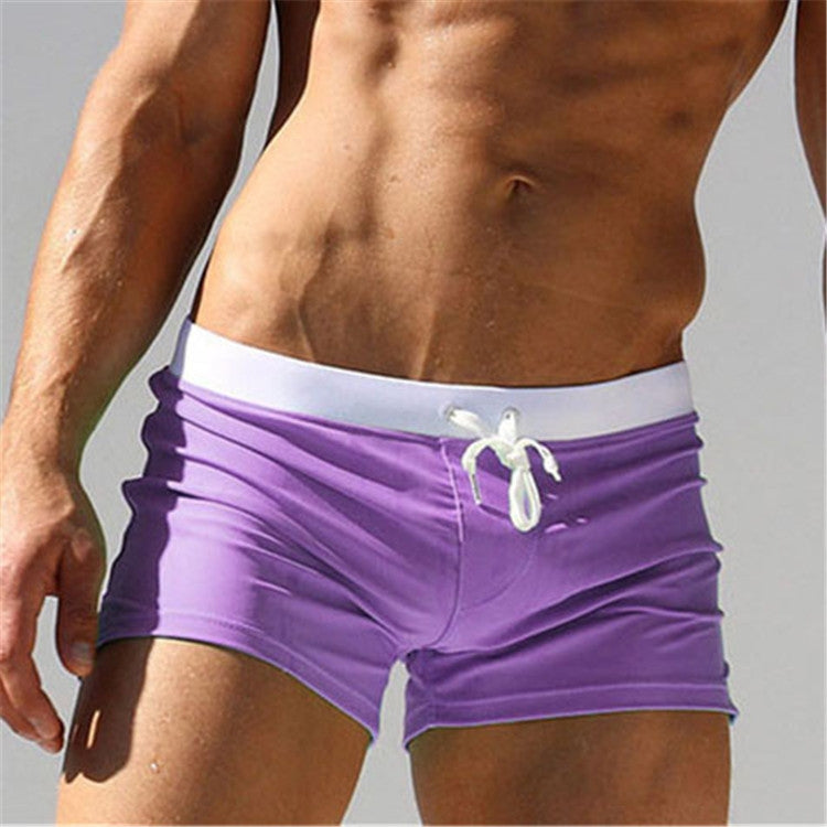 Men's purple swim shorts with white drawstring and side pockets, elastic waist