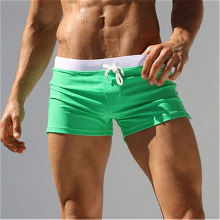 Men’s green swim shorts with white waistband and drawstring, back pocket seams.