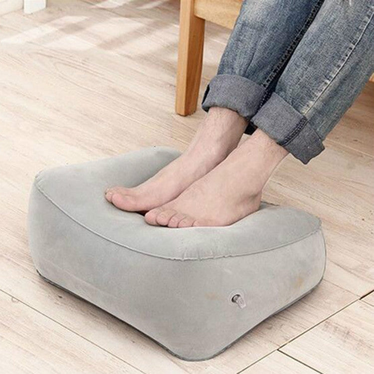 Gray inflatable foot rest pillow supporting seated feet, oval cup top