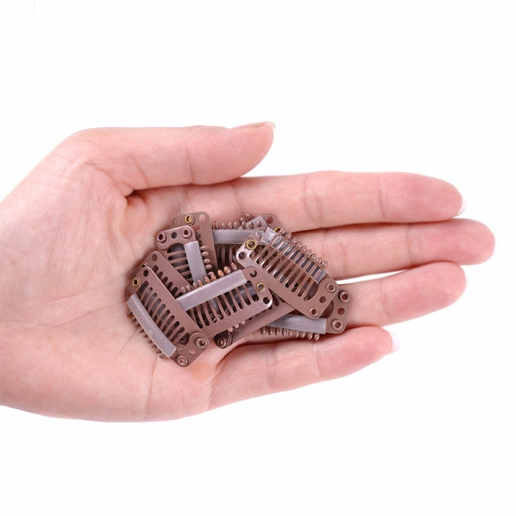 Hand holding several brown 9-tooth hair extension snap clips with metal comb teeth