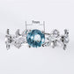 Silver-tone engagement ring with blue oval crystal center and vine leaf side accents