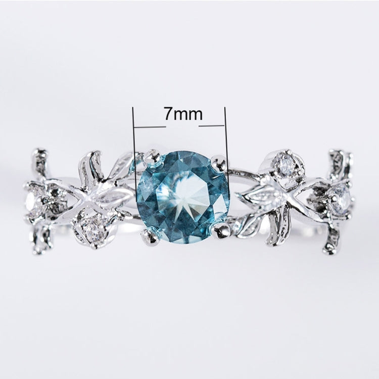 Silver-tone engagement ring with blue oval crystal center and vine leaf side accents