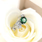 Silver-tone ring with green oval crystal centerpiece in flowerlike vine design