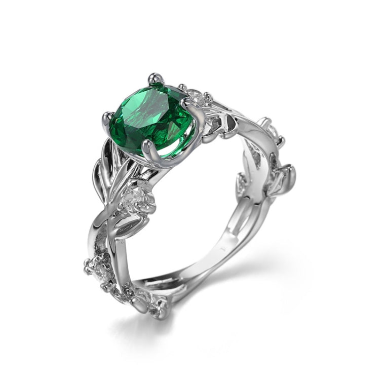 Silver-tone engagement ring with green oval crystal centerpiece and detailed vine band