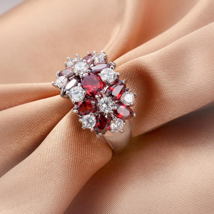 Sterling silver ring with red oval center and clear round crystals, close-up on fingers