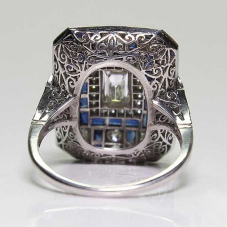 Silver-tone engagement ring with ornate filigree back and blue accent stones