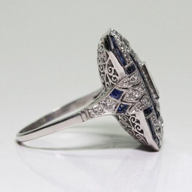 Square-cut crystal halo engagement ring, angled side view with dark blue accents