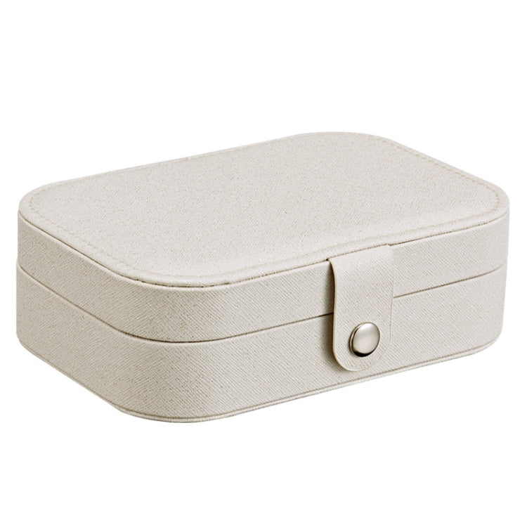 Portable jewelry storage box, light beige fabric with rounded lid and front clasp.