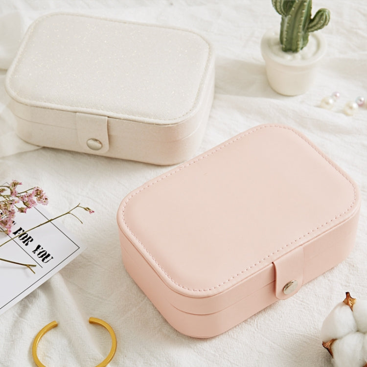 Portable jewelry storage box in blush pink, rounded hinged lid with front clasp.