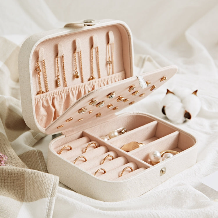 Open blush pink jewelry storage box with ring rows and earring plate along the top.